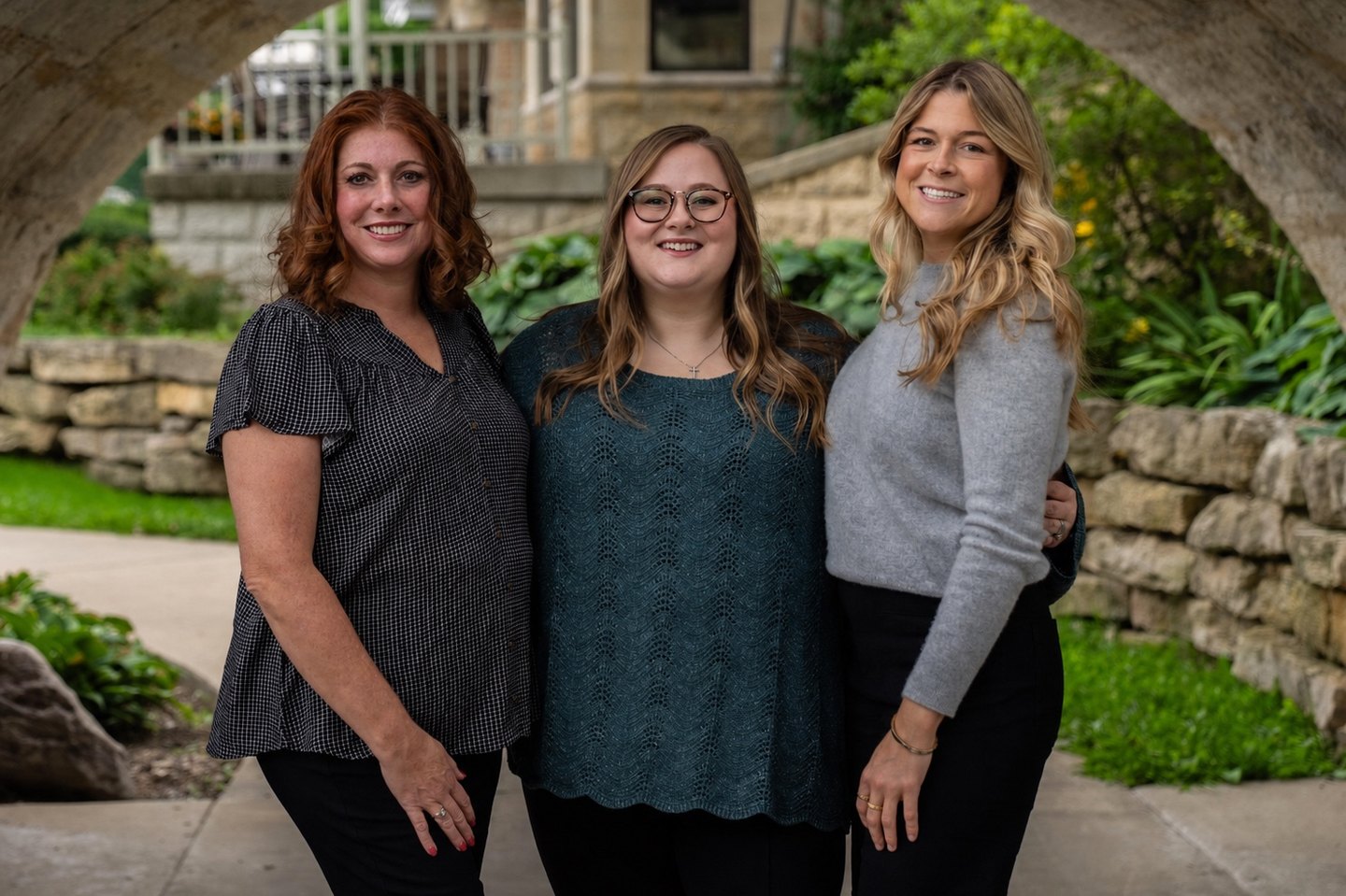 Kim Heine, Kayla Miller and Emma Martin standing together under a stone arch in Fort Atkinson